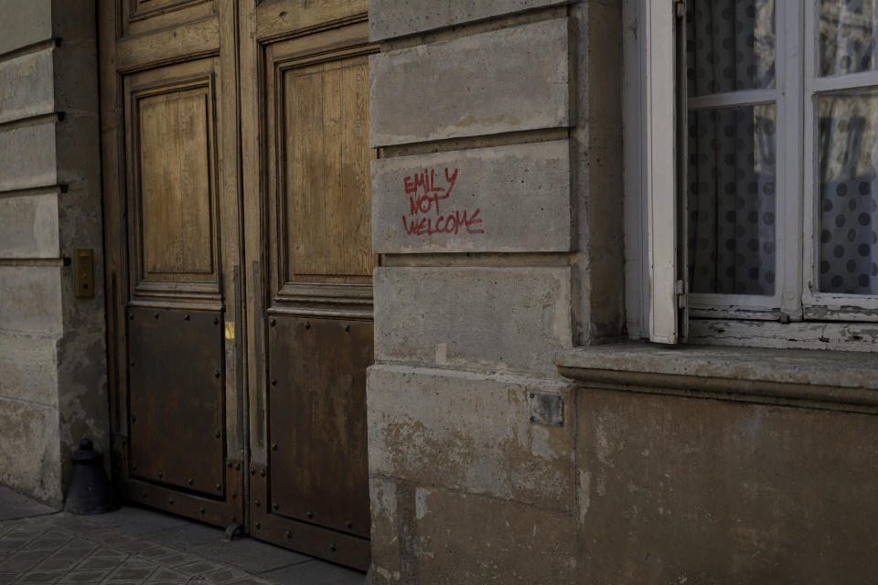 A graffiti reading "Emily Not Welcome" is scrawled on part of the facade of an apartment building where the fictional character Emily Cooper lives, at 1 Place de d'Estrapade, in Paris, Wednesday, April 19, 2023. The immense success of the Netflix series "Emily in Paris" has transformed a quiet, untouched square in the French capital into a tourist magnet. (AP Photo/Thibault Camus)