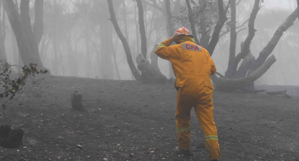 Firefighter walks across burnt ground in Mount Glasgow, Victoria, amid wild bushfires.
