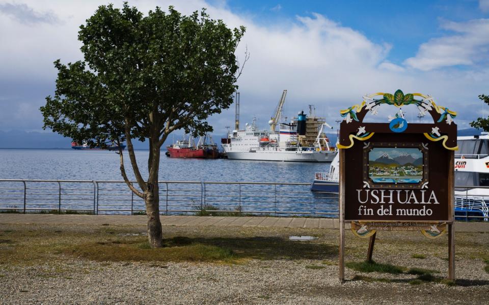 Sign announcing the end of the world in Ushuaia town and harbour in early morning light, Tierra del Fuego