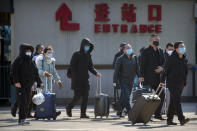 Travelers wear face masks as they walk outside the Beijing Railway Station in Beijing, Saturday, Feb. 15, 2020. People returning to Beijing will now have to isolate themselves either at home or in a concentrated area for medical observation, said a notice from the Chinese capital's prevention and control work group published by state media late Friday. (AP Photo/Mark Schiefelbein)