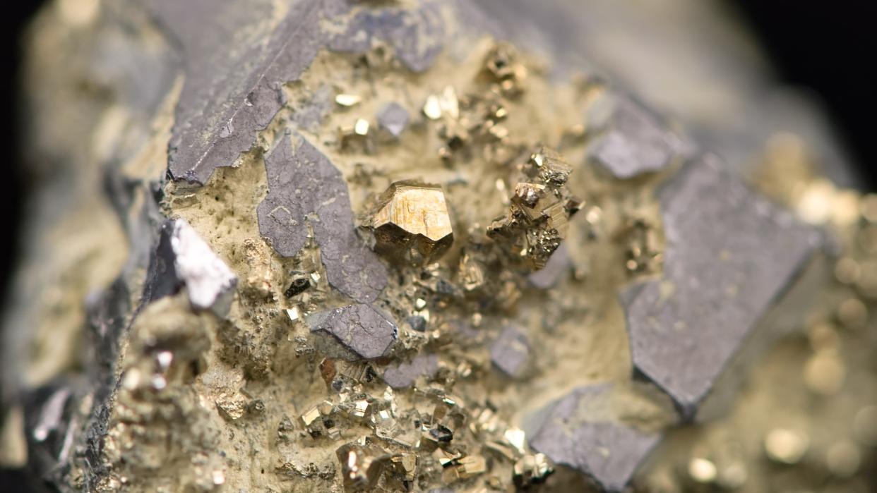  A close-up photo of a rock containing a raw gold nugget in a mine. 