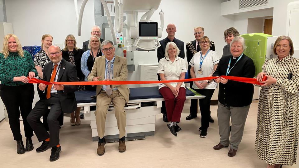 A group of people stand beside the new X-ray machine at the hospital