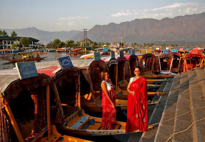 FILE PHOTO: Tourists pose on parked "Shikaras" or boats on the banks of Dal Lake in Srinagar