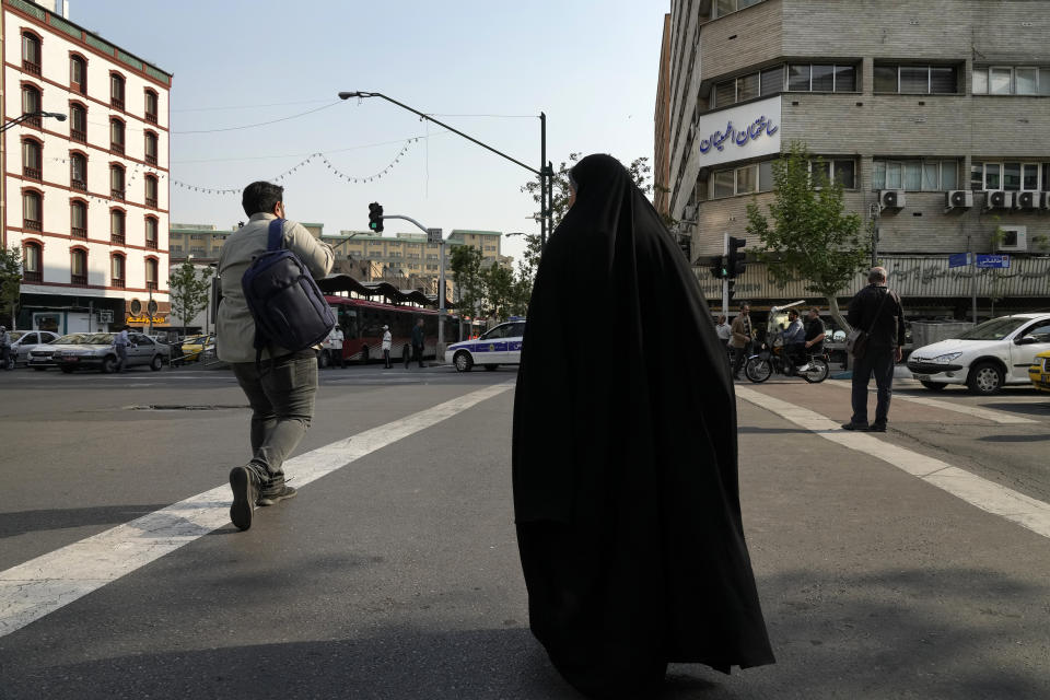 People cross an intersection in downtown Tehran, Iran, Sunday, April 14, 2024. Israel on Sunday hailed its air defenses in the face of an unprecedented attack by Iran, saying the systems thwarted 99% of the more than 300 drones and missiles launched toward its territory. (AP Photo/Vahid Salemi)