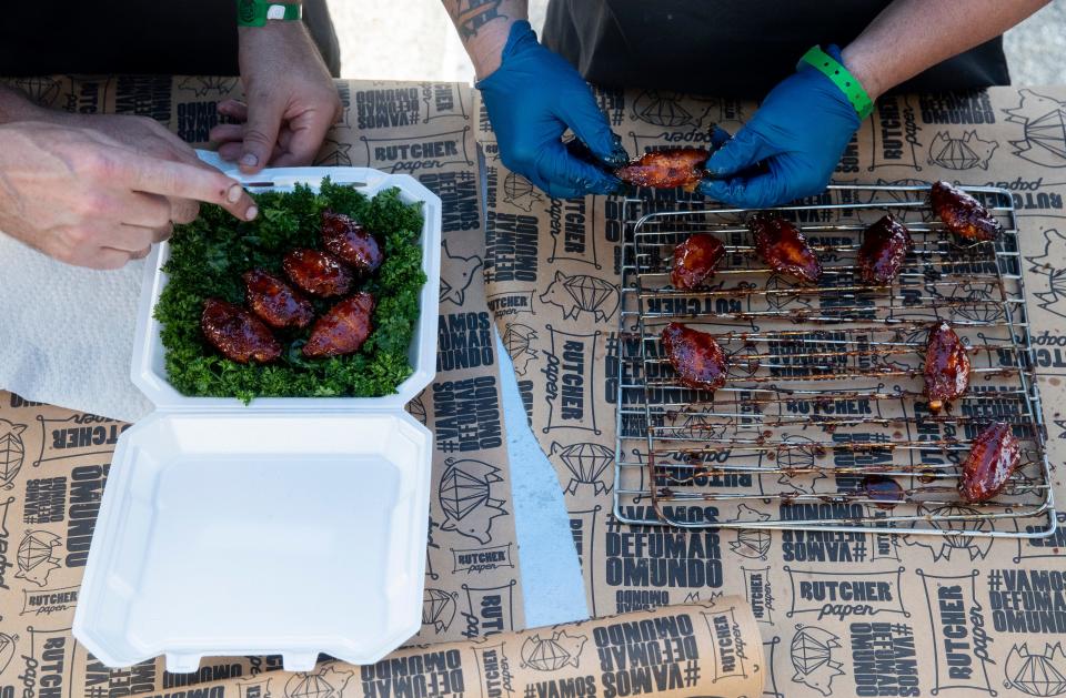 The Pig Diamonds team members Adriano Pedro and Bruno Panhoca get their box of chicken wings prepared to turn into the judges at their booth during the World Championship Barbecue Cooking Contest as part of the Memphis in May International Festival in Memphis, Tenn., on Thursday, May 16, 2024.