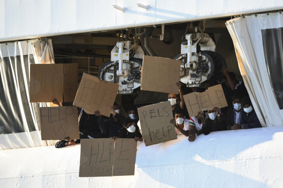 FILE - Migrants hold banners asking for help, from a deck of the Norway-flagged Geo Barents ship operated by Doctors Without Borders, in Catania's port, Sicily, southern Italy, Monday, Oct. 7, 2022. Italy's new government has blocked humanitarian rescue ships from accessing its ports, resulting in a stand-off with charities that patrol the deadly central Mediterranean Sea smuggling routes, used by people desperate to reach Europe for a new life. (AP Photo/Salvatore Cavalli, file)
