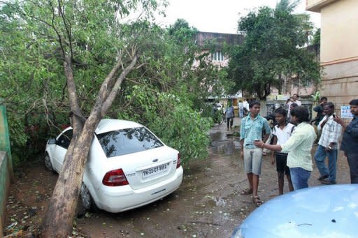 A tree rests on top of a car following heavy winds in the run up to Cyclone Nilam in Chennai. Thousands of people evacuated from their homes in southeast India Wednesday as a cyclone slammed into the coast, killing two people, according to reports, and causing an oil tanker to run aground