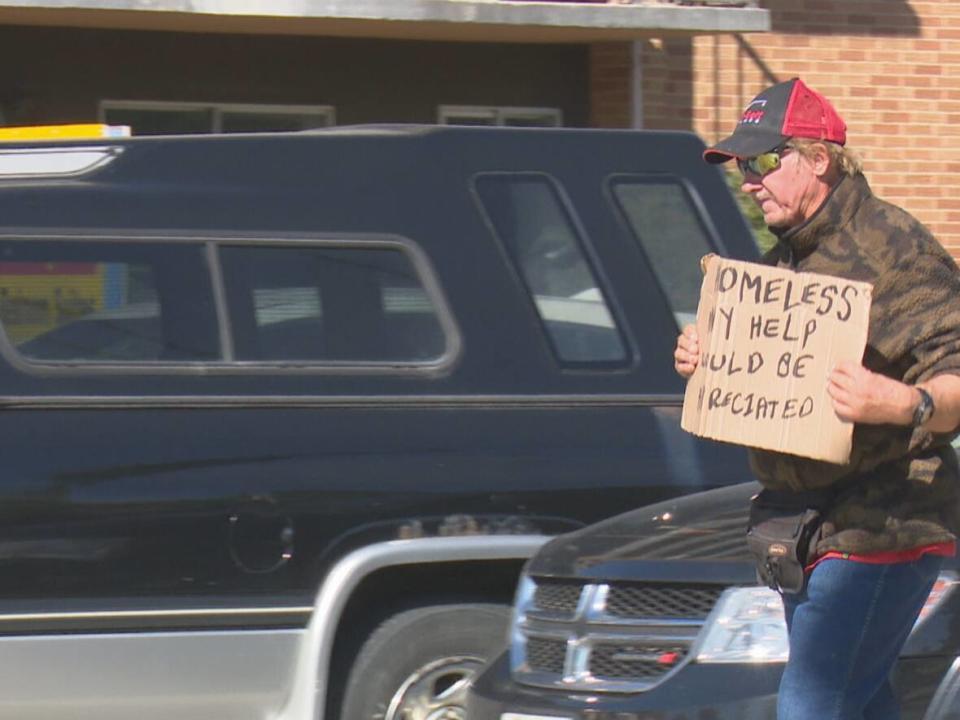 A panhandler works the intersection of Ouellette Avenue and Tecumseh Road. (Dale Molnar/CBC - image credit)