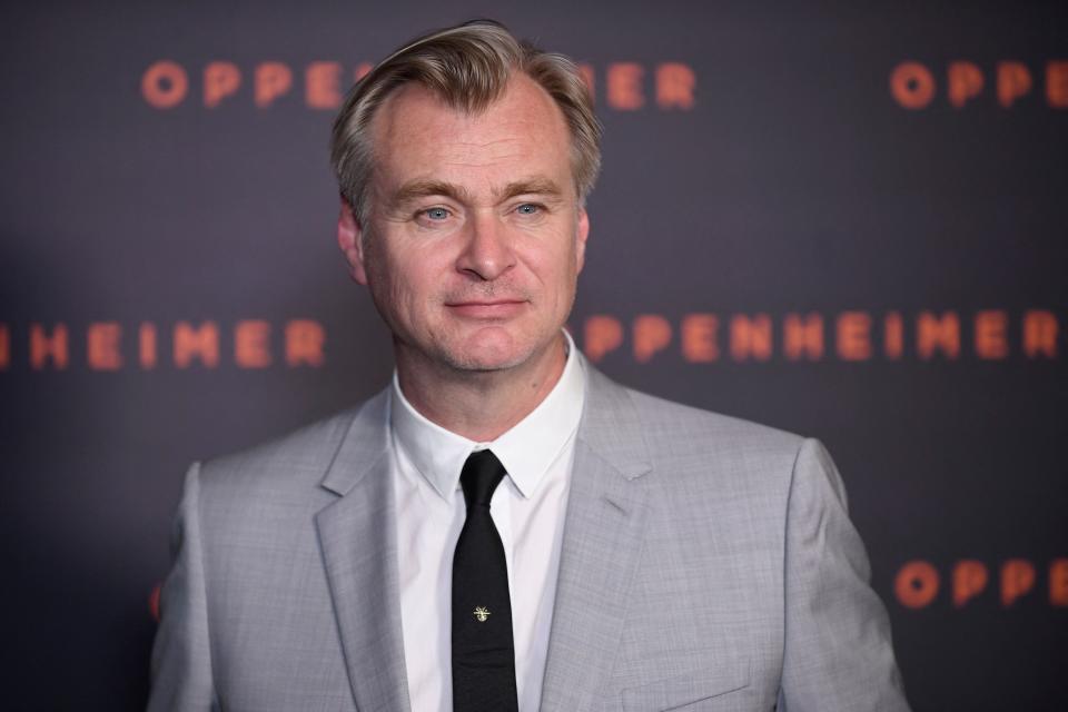 Christopher Nolan in a grey suit and dark tie