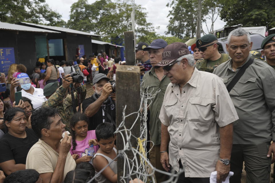 El presidente electo panameño, José Raúl Mulino, habla con un migrante venezolano, a la izquierda, y otros migrantes en un campamento después de que cruzaran caminando el Tapón del Darién desde Colombia, en Lajas Blancas, Panamá, el viernes 28 de junio de 2024. (Foto AP/Matías Delacroix )