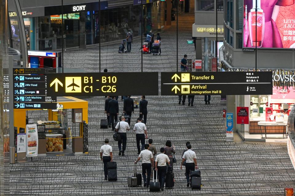 Singapore Airlines crew members and travellers walk along the transit hall of Changi International Airport terminal in Singapore on January 14, 2021. (Photo by Roslan RAHMAN / AFP) (Photo by ROSLAN RAHMAN/AFP via Getty Images)