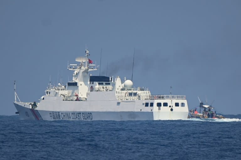 A China Coast Guard ship maneuvers past a Philippine fishing boat in the disputed South China Sea (Ted ALJIBE)