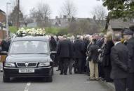 Mourners stand next to Martin McGuinness's hearse during his funeral at St Columba's Church in Londonderry, Northern Ireland, March 23, 2017. REUTERS/Clodagh Kilcoyne