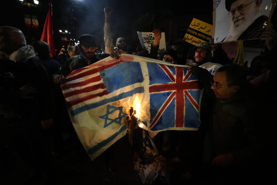 Iranian demonstrators burn representations of British, U.S. and Israeli flags during a protest against the U.S. and British military strike against Iranian-backed Houthis in Yemen, in front of the British Embassy in Tehran, Iran, Friday, Jan. 12, 2024. (AP Photo/Vahid Salemi)