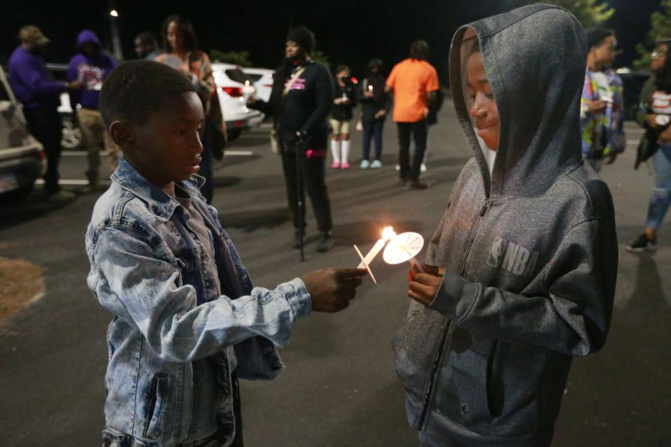 Jeremiah Armstrong helps Savannah Royal Lions teammate Jalen Jordan light his candle Tuesday evening during a Stop Gun Violence rally outside Memorial Stadium. Earlier this year a shooting occurred during a Royal Lions game at the Jennifer Ross Soccer Complex.