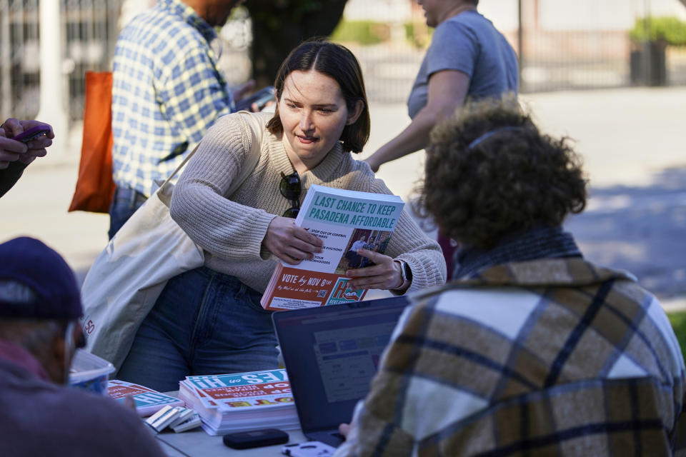 Volunteers of the Yes on Measure H! campaign pick up flyers at La Pintoresca Park to visit voters in their neighborhood in Pasadena, Calif., Saturday, Oct. 29, 2022. Cities across the country are pushing measures to stabilize or control rents when housing prices are skyrocketing. Voters from Orange County, Florida, and several California cities are asking voters to approve ballot measures that would cap rent increases. (AP Photo/Damian Dovarganes)