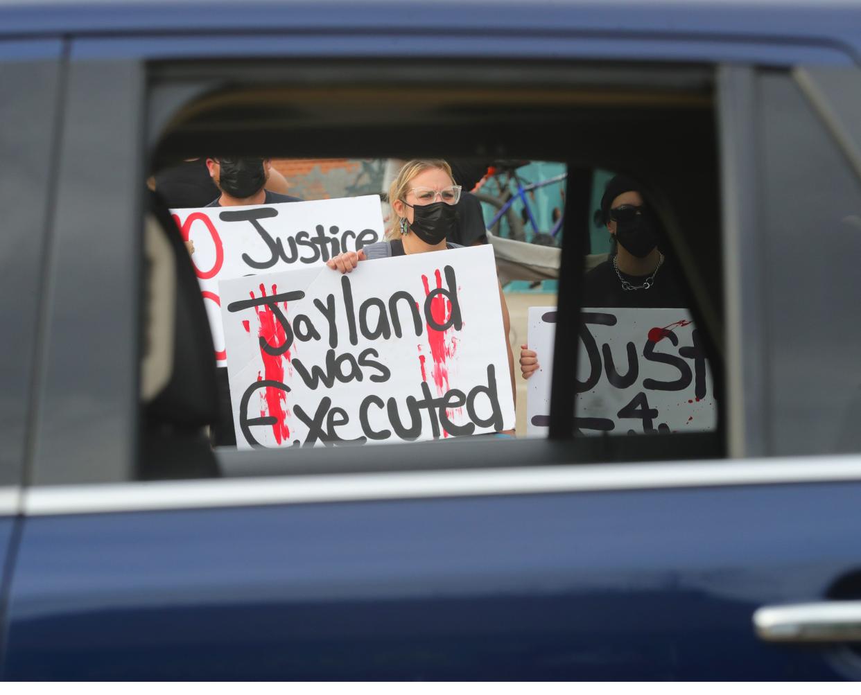 A protester is framed in the window of a stopped car Friday in the Highland Square neighborhood of Akron.
