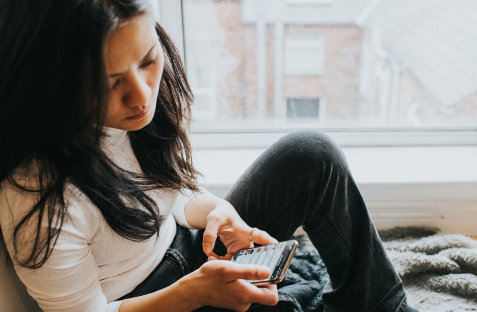 an elevated view of a concerned looking woman looking down at her mobile phone device space for copy