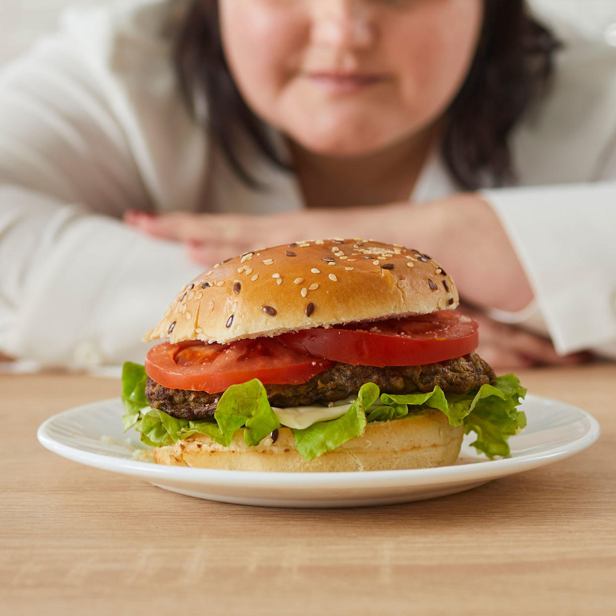 woman staring at a burger on a plate