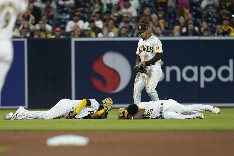 San Diego Padres shortstop C.J. Abrams, left, and left fielder Jurickson Profar, bottom right, react after colliding as center fielder Trent Grisham, center, looks on during the fifth inning of a baseball game against the San Francisco Giants, Thursday, July 7, 2022, in San Diego. Profar and Abrams collided as Abrams made a catch for an out against Giants' Tommy La Stella. (AP Photo/Gregory Bull)