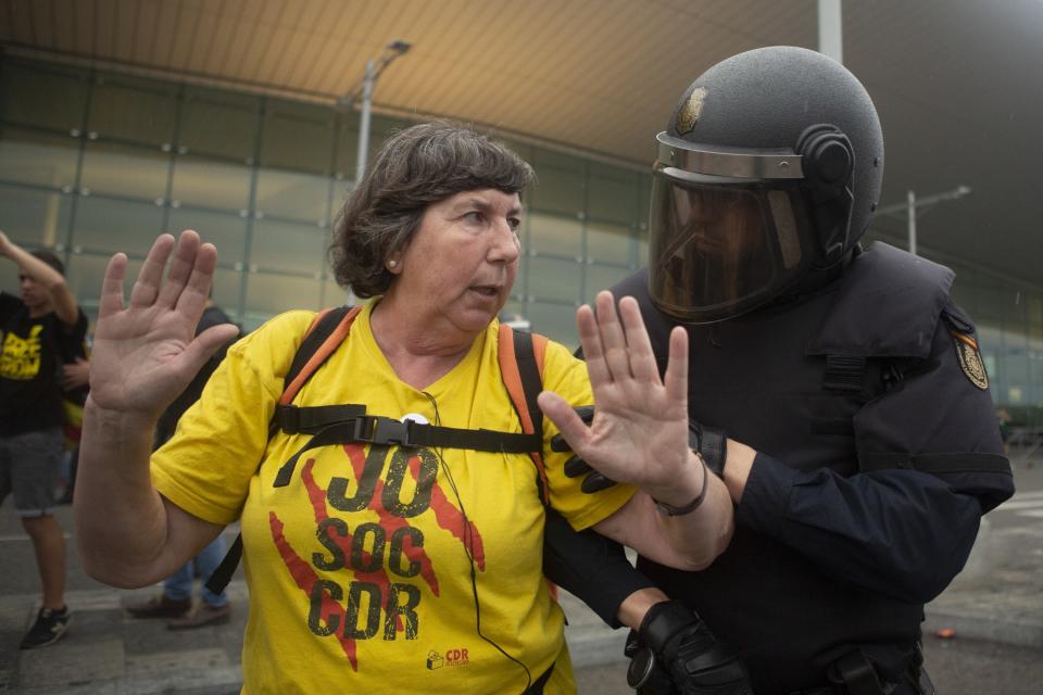 In this Monday, Oct. 14, 2019 photo, a Spanish police talks to a pro-independence protester during a demonstration at El Prat airport, outskirts of Barcelona, Spain. Riot police engaged in a running battle with angry protesters outside Barcelona's airport Monday after Spain's Supreme Court convicted 12 separatist leaders of illegally promoting the wealthy Catalonia region's independence and sentenced nine of them to prison. (AP Photo/Joan Mateu)