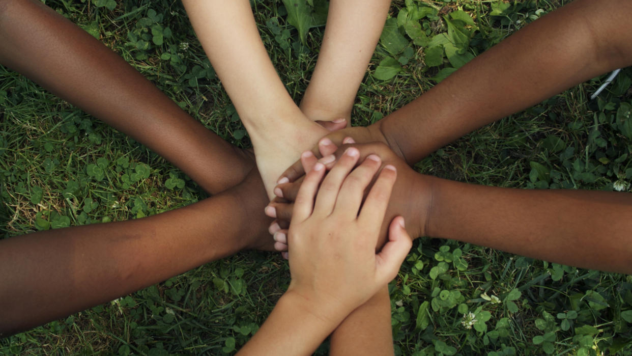  A group holding hands against grass. 