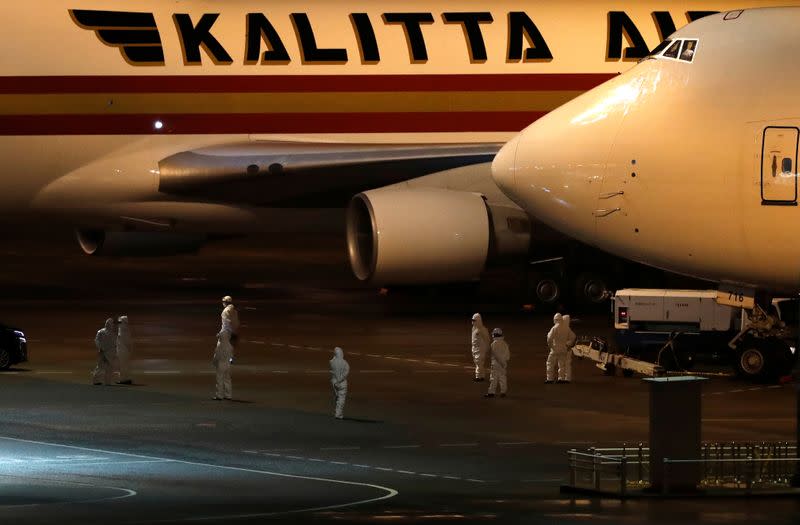 People wearing protectivie suits are seen near an airplane prepared for the U.S. passengers of the cruise ship Diamond Princess, where dozens of passengers were tested positive for coronavirus, in Yokohama