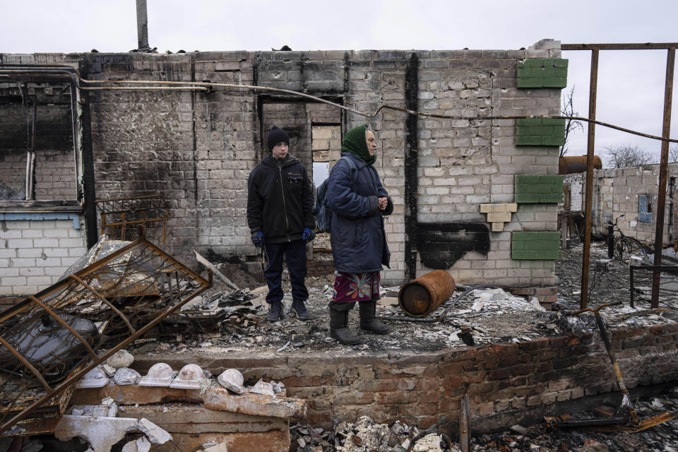 Danyk Rak, 12, and his grandmother Nina Vynnyk stand on the debris of their house which was destroyed by Russian forces' shelling in the outskirts of Chernihiv, Ukraine, Wednesday, April 13, 2022. After the shelling Danyk's mother Liudmila Koval had to have her leg amputated and was injured in the abdominal cavity. She is still waiting for proper medical treatment. (AP Photo/Evgeniy Maloletka)