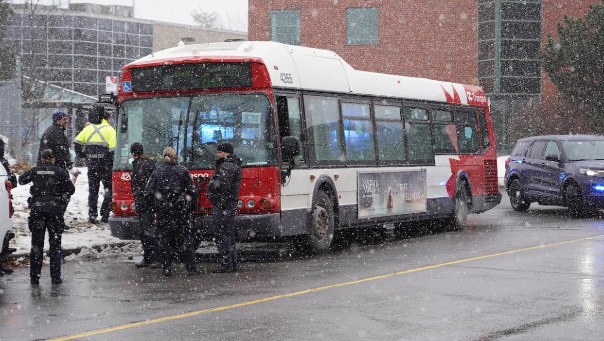 Emergency crews stand near an OC Transpo bus in Ottawa on Dec. 11, 2023. A bus driver suffered minor burns, according to paramedics. (Francis Ferland/CBC - image credit)