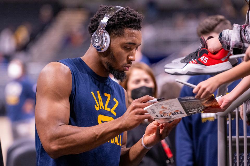 Utah Jazz guard Donovan Mitchell (45) gives an autograph for a fan as he leaves the court after warming up before an NBA basketball game against the Indiana Pacers in Indianapolis, Saturday, Jan. 8, 2022. (AP Photo/Doug McSchooler).