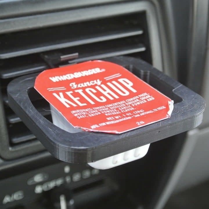 a black vent clip with one packet of ketchup inserted 