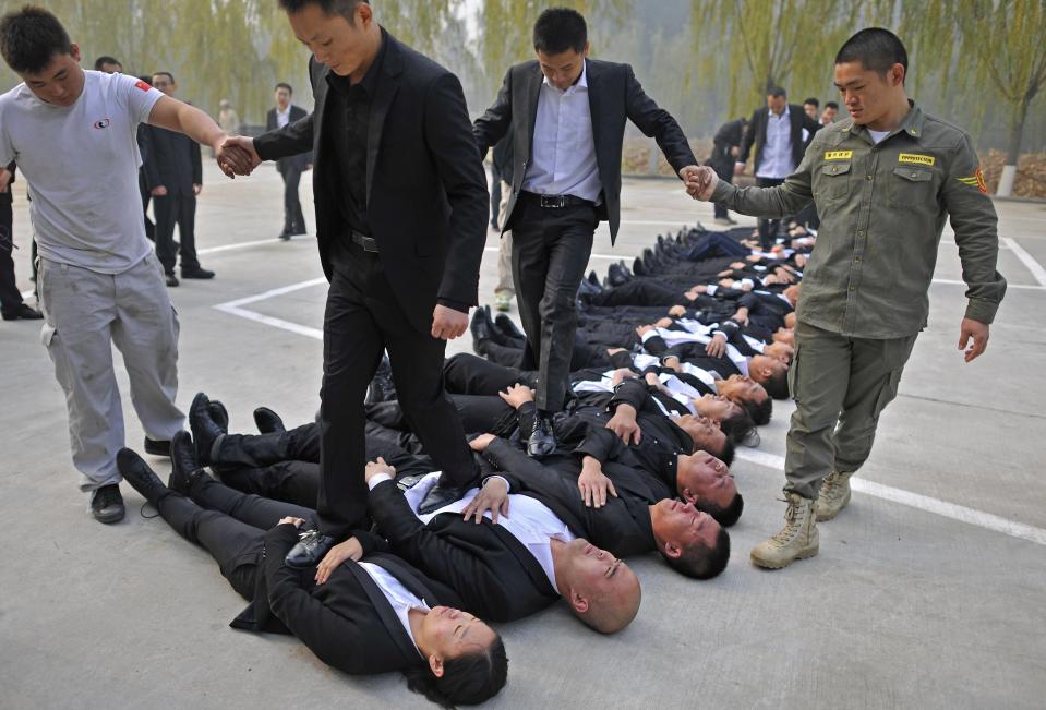 Trainees walk over the bodies of their fellow trainees during the Tianjiao Special Guard/Security Consultant Ltd. bodyguard training camp in Beijing