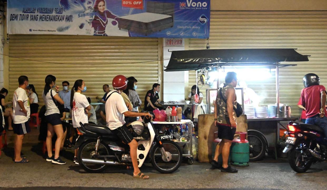 A queue in Malaysia for a roadside hawker in Penang, illustrating Malaysians eating out.