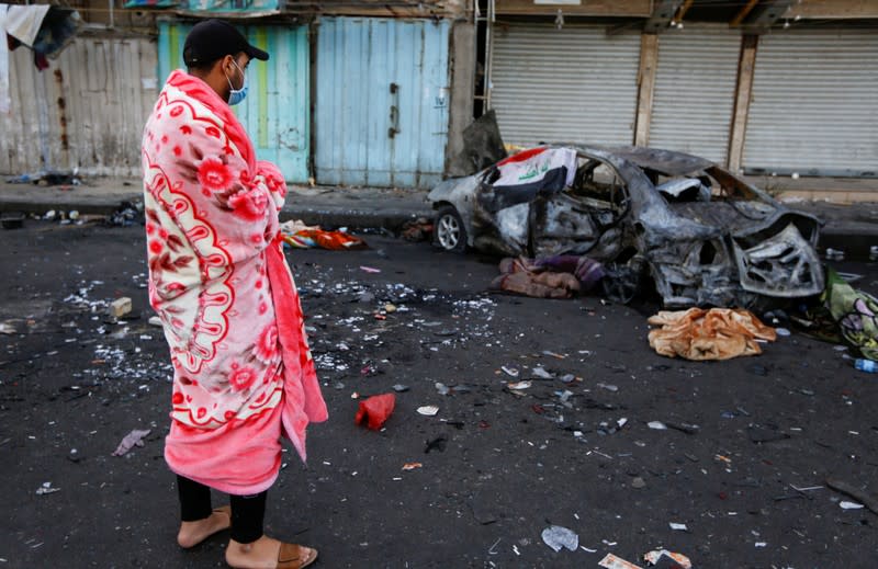 An Iraqi demonstrator looks at the site where an improvised explosive device went off in Baghdad