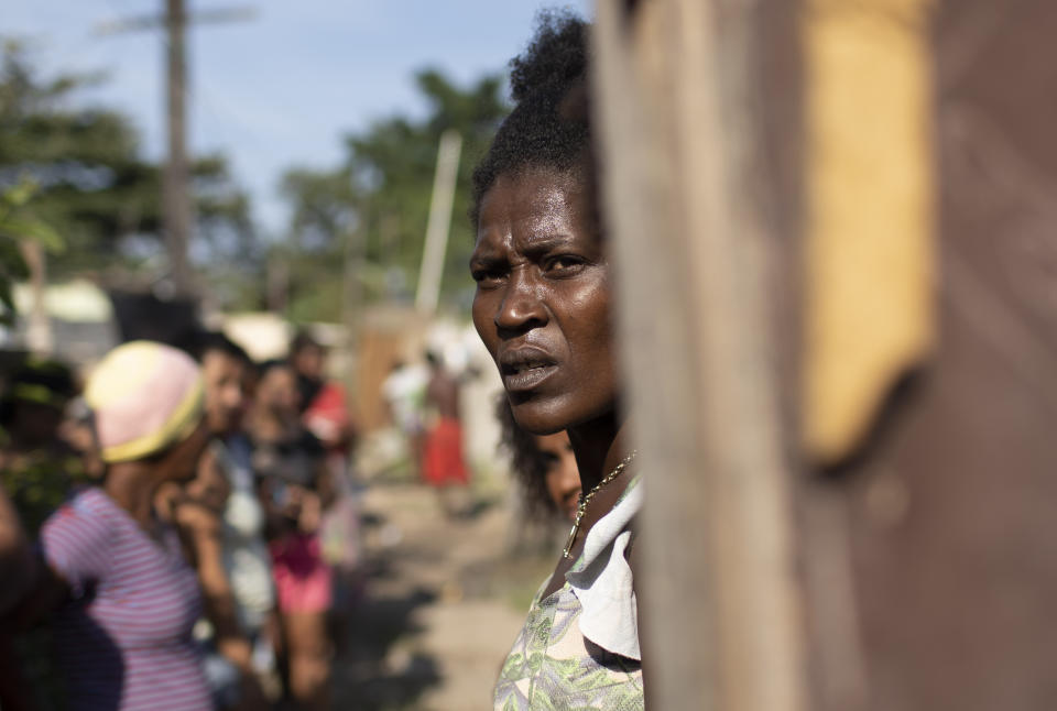 Gracieli Lima, 34, waits for food donated by the Covid Without Hunger program in the Jardim Gramacho slum of Rio de Janeiro, Brazil, Saturday, May 22, 2021. The federal government withdrew the welfare lifeline at the end of 2020, then resumed payments in April, but for only two-thirds as many people, who now receive less than half the previous monthly amounts. (AP Photo/Silvia Izquierdo, File)