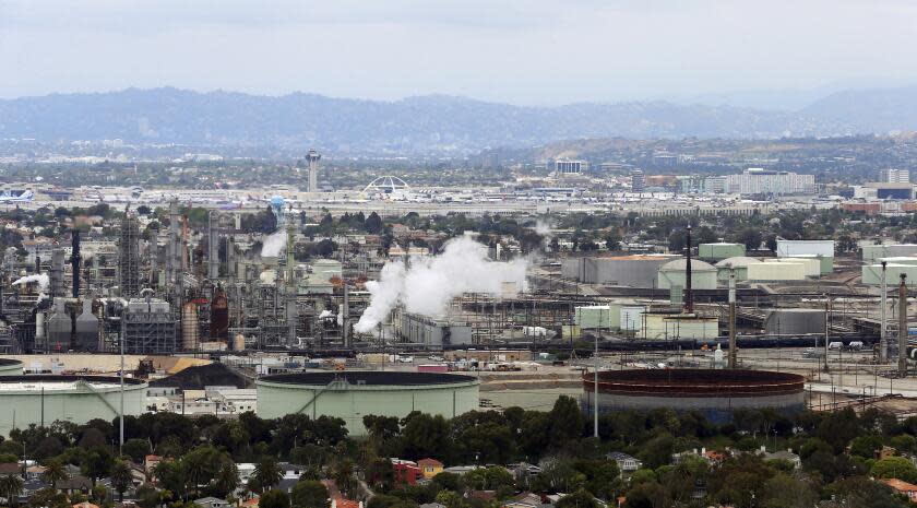 FILE - This May 25, 2017 aerial photo shows the Standard Oil Refinery in El Segundo, Calif., with Los Angeles International Airport in the background and the El Porto neighborhood of Manhattan Beach, Calif., in the foreground. A plan to extend California's cap-and-trade program for another decade looks beyond cutting greenhouse gas emissions and takes aim at toxic air in the polluted neighborhoods around refineries and factories. (AP Photo/Reed Saxon, File)