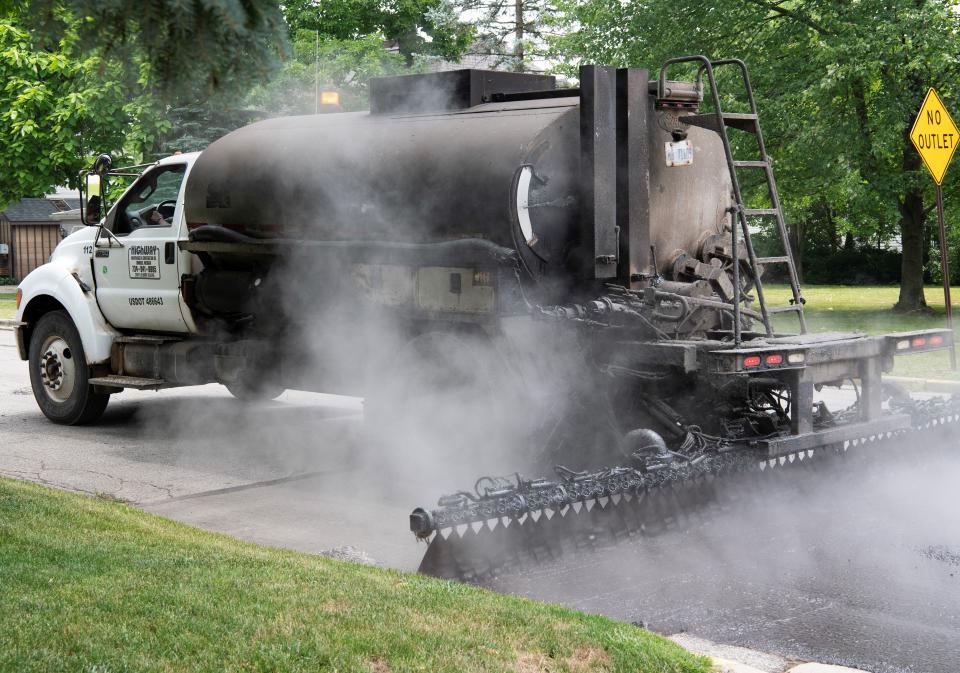 Road crews from Highway Maintenance & Construction, Romulus, are seen performing chip and fog seal work to Adrian roads and streets around the campus of Adrian College in this file photo from June 2023.