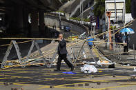 A man crosses in front of a roadblock set up by pro-democracy protesters outside the Hong Kong Baptist University, in Hong Kong, Wednesday, Nov. 13, 2019. Police have increased security around Hong Kong and its university campuses as they brace for more violence after sharp clashes overnight with anti-government protesters. (AP Photo/Vincent Yu)