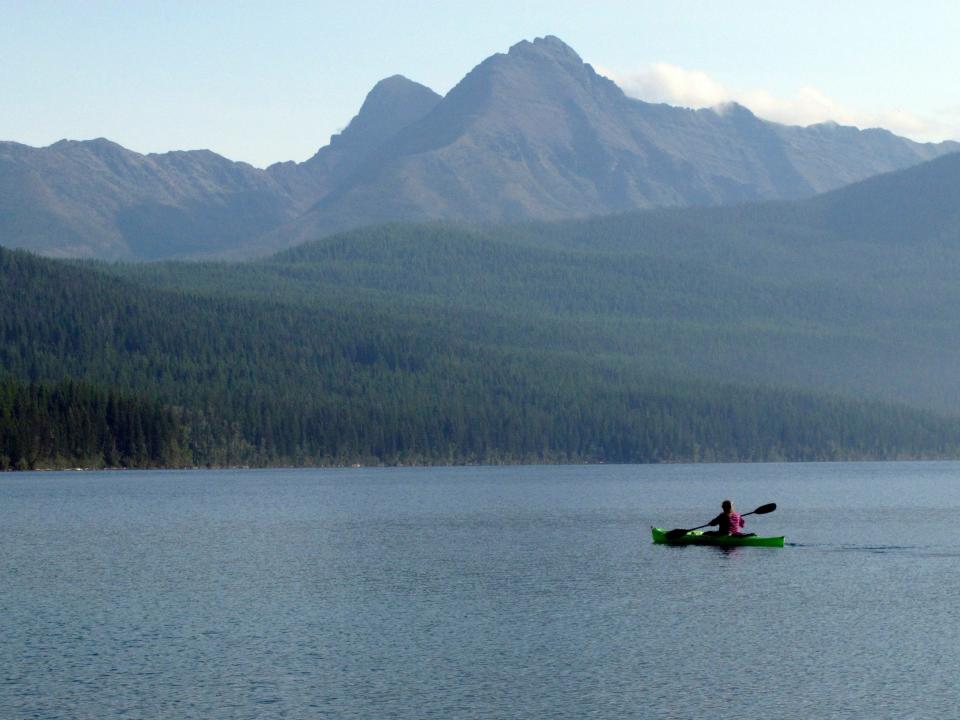 Kayaker paddles in lake at Glacier National Park in Montana