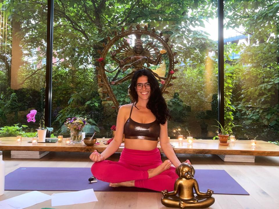 Jenna Goldman in a yoga pose on a yoga mat, smiling