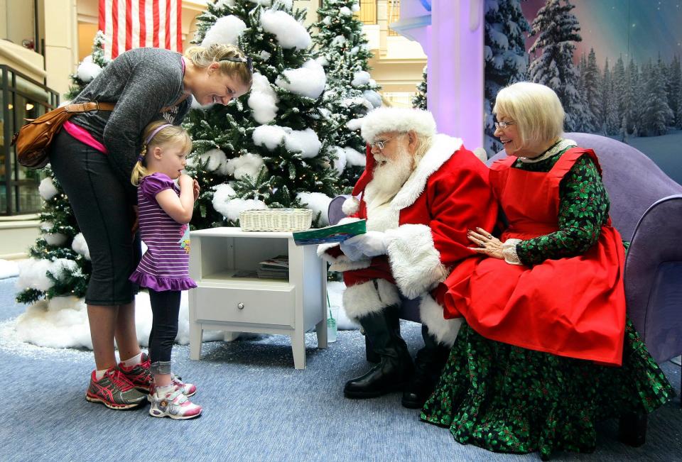 Katie Bowen, (L), of Loxahatchee comforts her three year old daughter Eryn, (2L), while talking to Santa and Mrs. Claus at the Mall at Wellington Green Nov 06, 2014, in Wellington. "She was afraid of them last year, so the fact she is talking is kind of neat," said Mrs. Bowen. Santa and Mrs. Claus will be at the mall until December 24th.