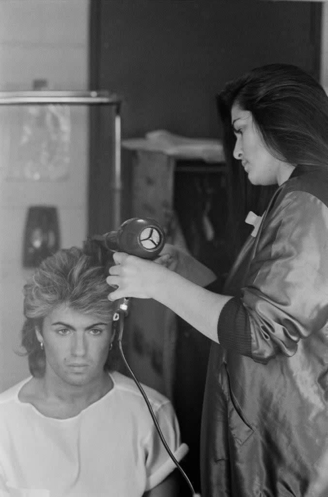 <p>Wham!'s lead singer, George Michael, gets his impressive mane blown out by a hairdresser on the Australian leg of the band's The Big Tour in 1985. </p>