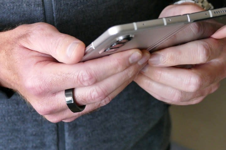 The Oura ring worn on a man's finger while holding the Galaxy Z Fold 3.