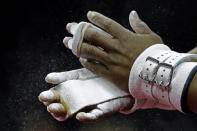 Simone Biles chalks her hands before working on the uneven bars during practice for the U.S. Gymnastics Championships Wednesday, Aug. 7, 2019, in Kansas City, Mo. (AP Photo/Charlie Riedel)