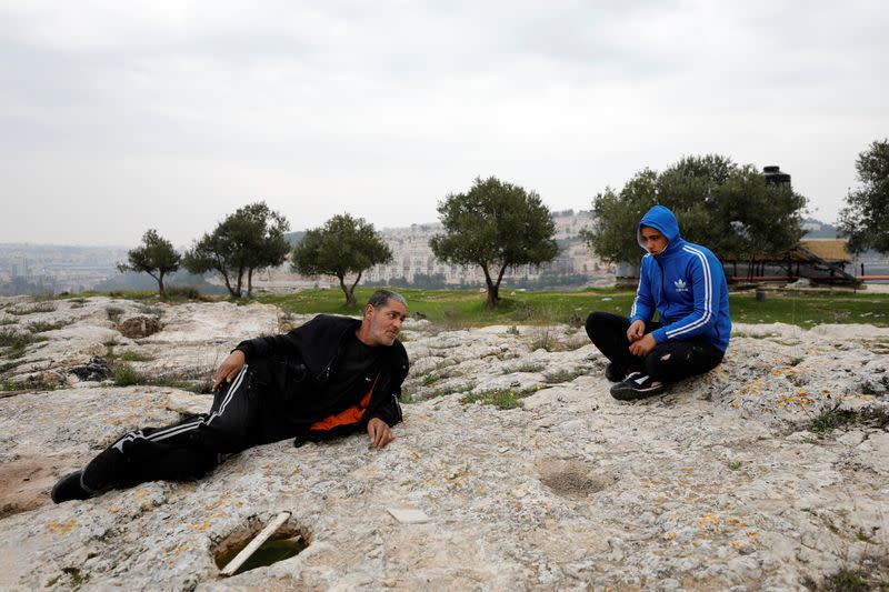 Palestinian man Omar Hajajla, who is cut off with his family from the rest of their village by the Israeli wall, chats with his son in Al-Walaja village near Bethlehem, in the Israeli-occupied West Bank