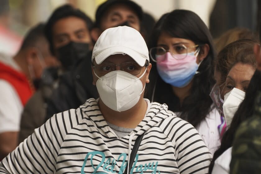 People wait outside a pharmacy to get tested for COVID-19, in Mexico City, Monday, Jan. 10, 2022. (AP Photo/Marco Ugarte)