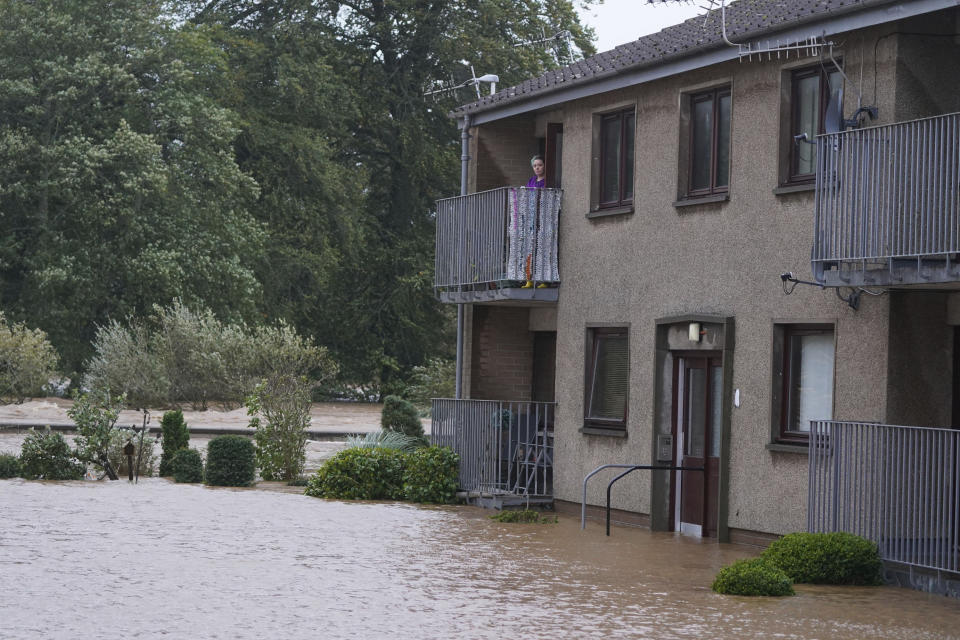 A person stands on a balcony of a flooded property in Brechin, Scotland, Friday Oct. 20, 2023. The gale-force winds are expected to hit hardest the eastern part of Denmark's Jutland peninsula and the Danish islands in the Baltic Sea. But the British Isles, southern Sweden, northern Germany and parts of Norway also on the path of the storm, named Babet by U.K.’s weather forecaster, the Met Office. (Andrew Milligan/PA Wire/PA via AP)