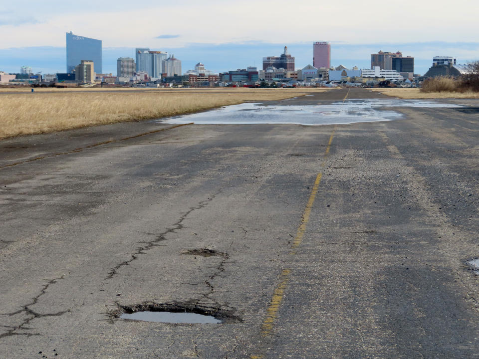 FILE: A pot-holed runway at the former Bader Field airport site is backdropped by casinos on Feb. 18, 2022, in Atlantic City, N.J. Two Philadelphia developers want to build a $3 billion housing, office and retail project on the site of the historic former airport in Atlantic City, the latest proposal for one of the largest tracts of buildable land near the ocean on the U.S. East Coast. (AP Photo/Wayne Parry, File)