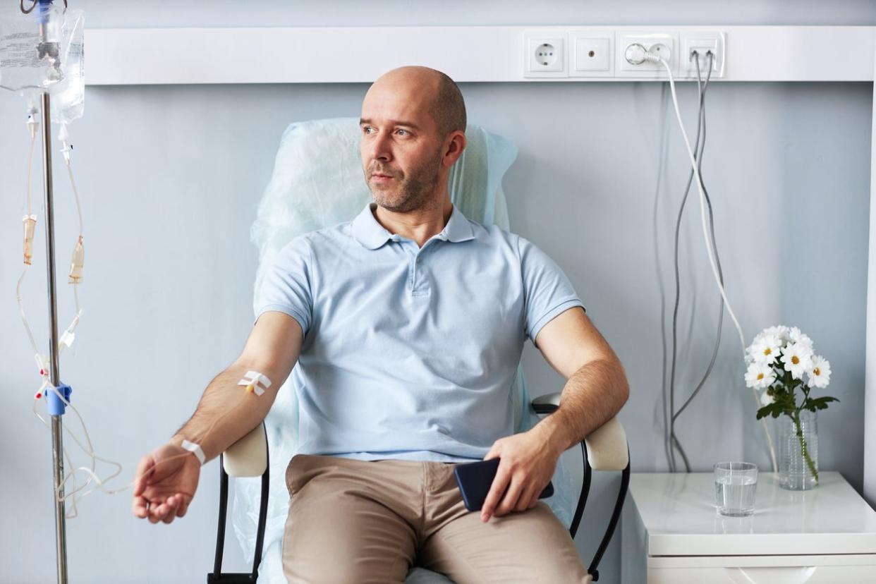 Adult man sitting in chair with IV drip during treatment