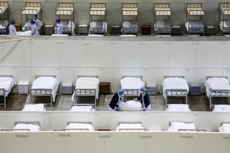 En esta imagen, tomada el 5 de febrero de 2020, personal médico prepara camas en un centro de convenciones reconvertido en hospital para pacientes con coronavirus, en Wuhan, la ciudad en el epicentro del brote, en la provincia de Hubei, China. (Chinatopix via AP)
